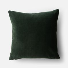 a dark green velvet pillow on a white background, with the corded fabric covering it