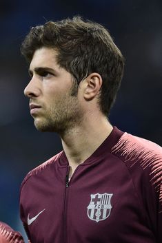 a close up of a soccer player wearing a red jacket and looking off to the side