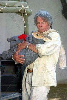 an old man holding a stuffed animal in his arms