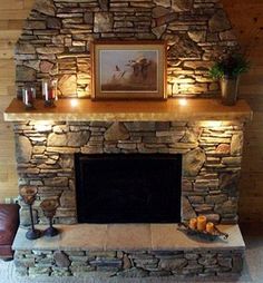 a stone fireplace with candles on it and a painting above the mantel in front of it