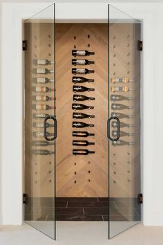 a wine cellar with glass doors and bottles on the wall