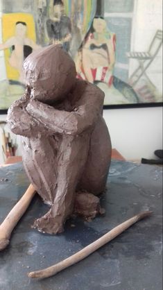 a clay sculpture sitting on top of a table next to a wooden stick and paintbrush