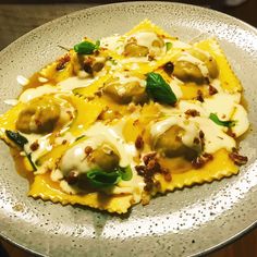 a white plate topped with ravioli covered in cheese