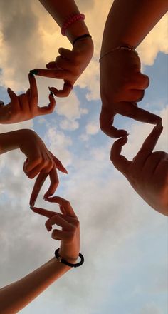 several hands reaching up into the air to form a circle with their fingertipss together