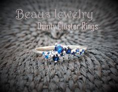 a close up of a ring with blue stones on it and the words beaus jewelry dainty cluster rings