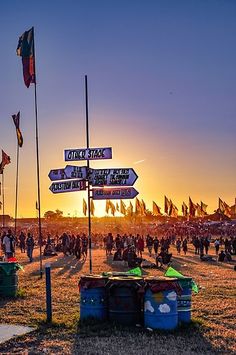 a group of people standing on top of a grass covered field next to street signs