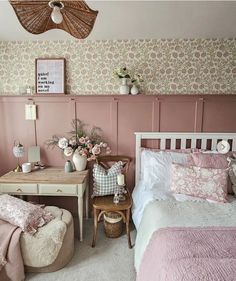 a bedroom decorated in pink and white with flowers on the headboard, bedding, and desk