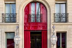 a large red door is in front of a tall building with windows and balconies