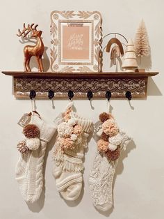 three knitted stockings hanging on a wall with a deer and christmas tree in the background