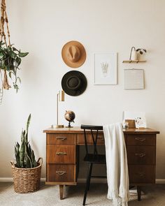 a room with a desk, chair and hat on the wall above it is a hanging plant