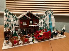 a lego christmas scene with santa's sleigh and reindeers in front of a house