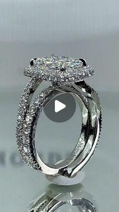 a close up view of a diamond ring on a table with the reflection of it