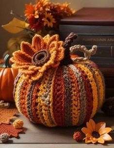 a crocheted pumpkin sitting on top of a table next to some books and flowers