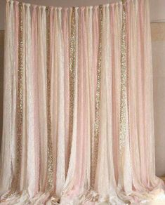 a pink and gold curtain with sequins hanging from it's side in front of a wall