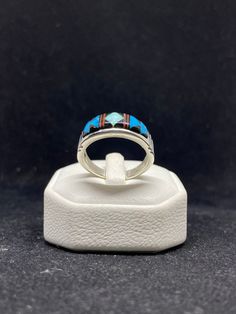 Contemporary handmade Native American Navajo inlay sleeping beauty turquoise, white fire opal, ox blood coral & Jet sterling silver mens band ring Size 12.5 stamped & signed by artist Rick.T This ring is made with the famous Navajo style; Inlay Inlay is the process of hand-cutting each stone to fit in a flush surface. As you can see, the stones are also slightly raised to give it a textured feeling. There are 25 hand cut stones soldered and inlayed into a silver bezel with gorgeous silver work s Mens Band Rings, Navajo Style, Silver Work, Sleeping Beauty Turquoise, Sterling Silver Mens, Mens Band, Ox, Fire Opal, Band Ring