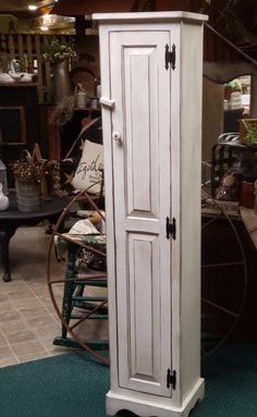 a tall white cabinet sitting on top of a green rug