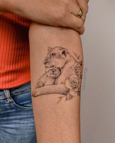 a woman's arm with a lion and roses tattoo on the left side of her arm