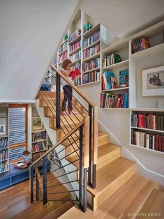 there is a young boy walking up the stairs in this room with bookshelves