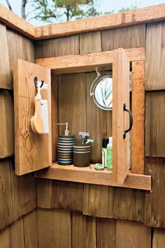 a wooden shelf with pots and pans in it on the side of a building