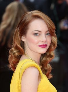 a woman with bright red hair and blue eyes wearing a yellow dress at an event