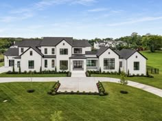 an aerial view of a large white house in the middle of a lush green field