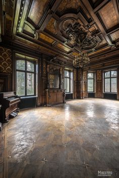 an empty ballroom with chandelier, piano and windows