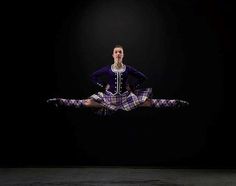 a woman in a purple and white dress is doing a trick on a black background