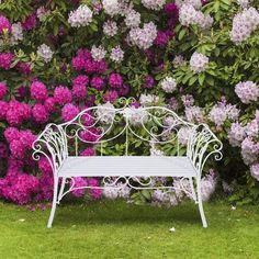 a white bench sitting in front of purple flowers