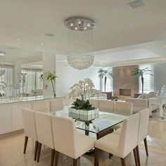 a dining room table with white chairs and a chandelier hanging from the ceiling