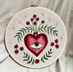 a red heart with an eye in the center surrounded by flowers and leaves on a white background