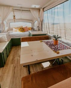 the inside of a camper with two beds and a table in front of it