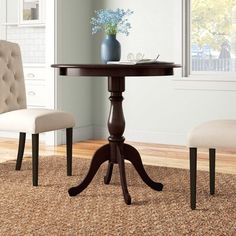 a small table with two chairs and a vase on top of it in front of a window