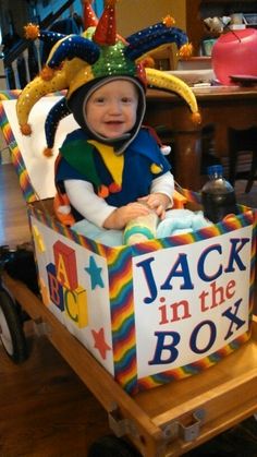 a baby sitting in a toy wagon with a birthday hat on it's head