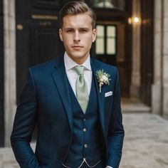 a man in a blue suit and green tie standing on the street with his hands in his pockets