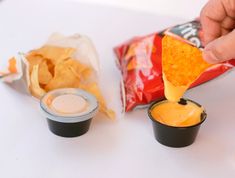 a person dipping some chips into small cups