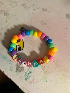 a close up of a colorful bracelet on a white surface with writing that says mama