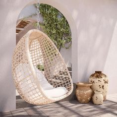 a white hanging chair next to a potted plant