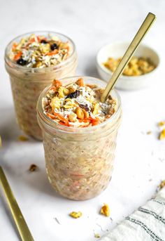 two jars filled with food sitting on top of a white table next to spoons