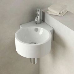 a white bathroom sink sitting next to a wall mounted faucet