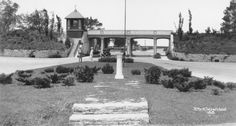 an old black and white photo of a clock tower in the middle of a park