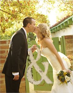 a man and woman kissing in front of a wooden sign that says 8 and 8