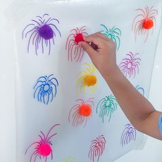 a child's hand writing on a white board with colored fireworks