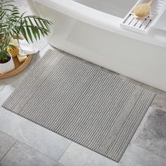 a bathroom with a bathtub, rug and plants on the floor next to it