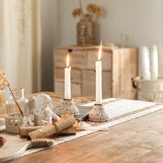 two candles sitting on top of a wooden table next to other objects and decor items