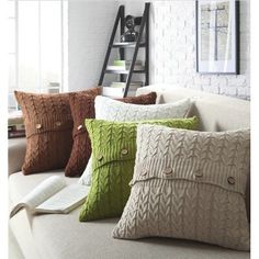 four pillows on a couch with a ladder in the background and a book laying on it