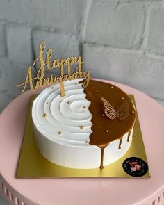 a birthday cake with white frosting and gold lettering on top that says happy anniversary