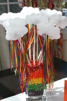 a vase filled with candy and clouds on top of a table