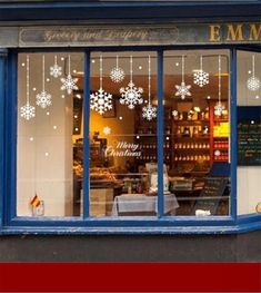 a store front with snowflakes on the windows and decorations hanging from the window