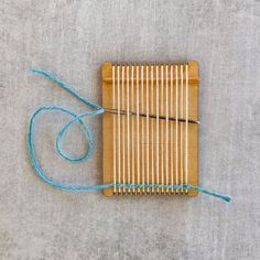 a bamboo loom sitting on top of a gray floor next to a blue string