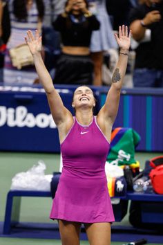 a female tennis player raising her arms in the air